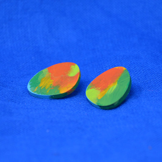 A pair of teardrop-shaped wooden earrings featuring a vibrant, multicolored hand-painted design with swirls of orange, green, and yellow on a bright blue textured background.