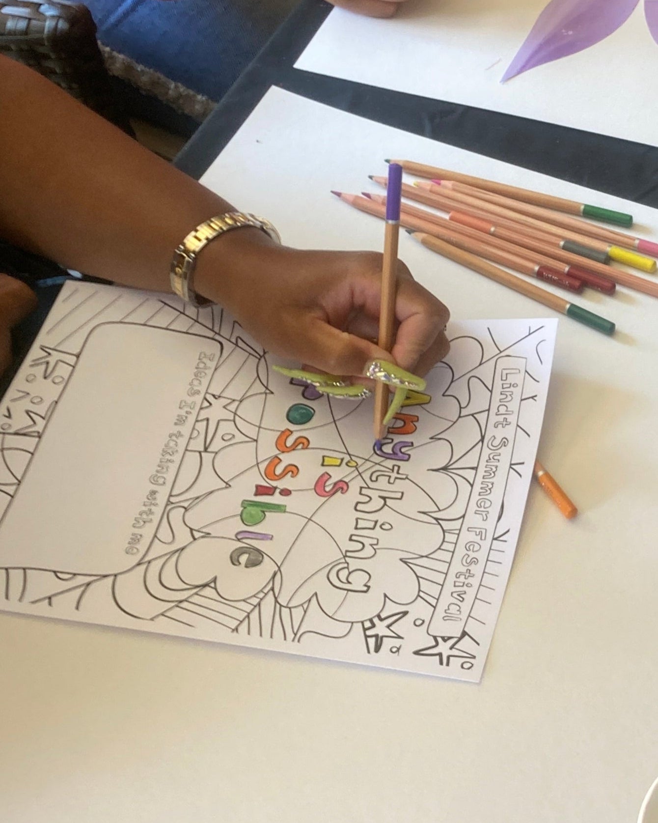 Two people coloring at a table with coloring books and pencils.