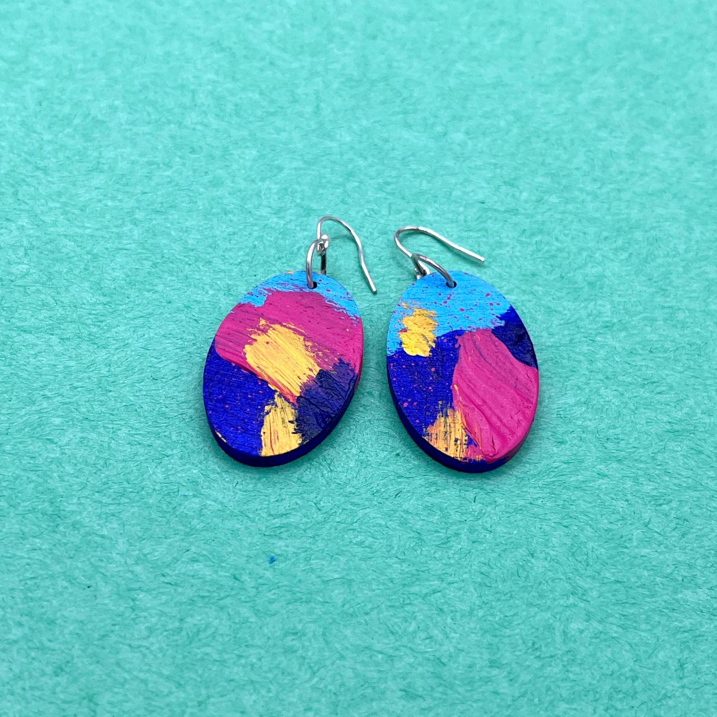 Colorful oval earrings on a teal background