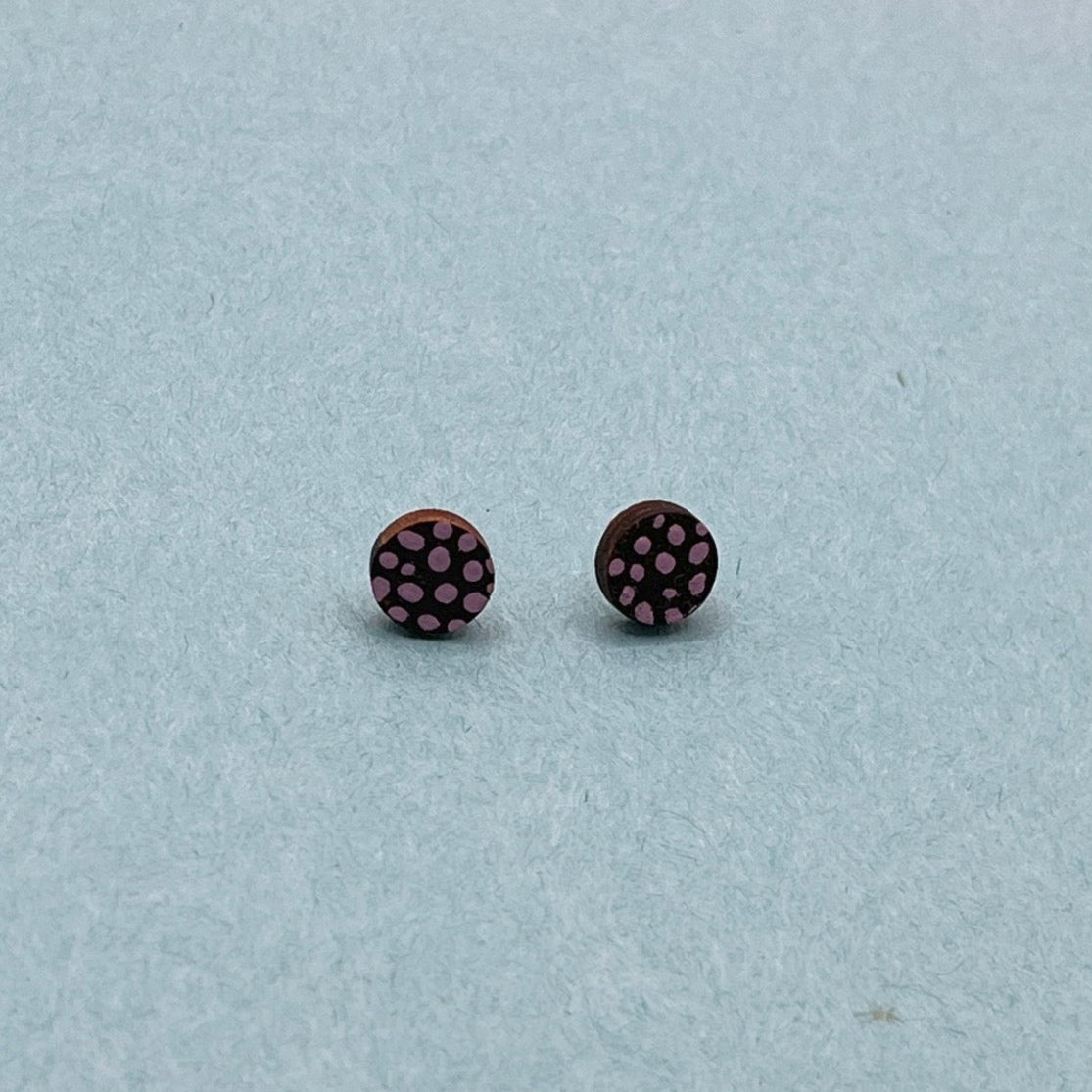 Black stud earrings on a light blue background with colorful geometric shapes.