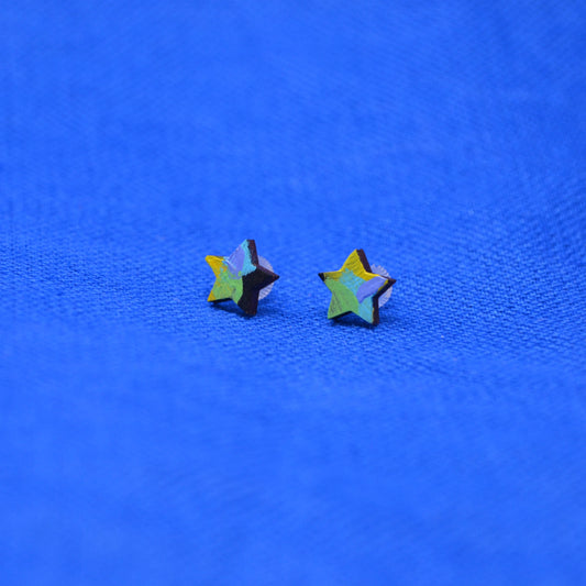 Two small star-shaped stud earrings with a black, yellow, green, purple and blue painted pattern, displayed on a textured blue background.