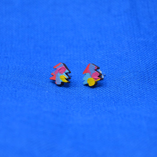 A pair of small multicolor tree stud earrings on a textured bright blue background.