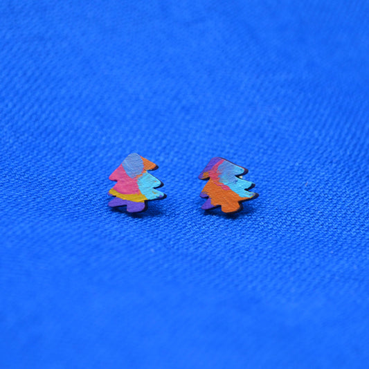 A pair of small, colorful stud earrings shaped like stylized trees, featuring a multicolor pattern of pink, orange, blue, and purple, set against a textured bright blue background.