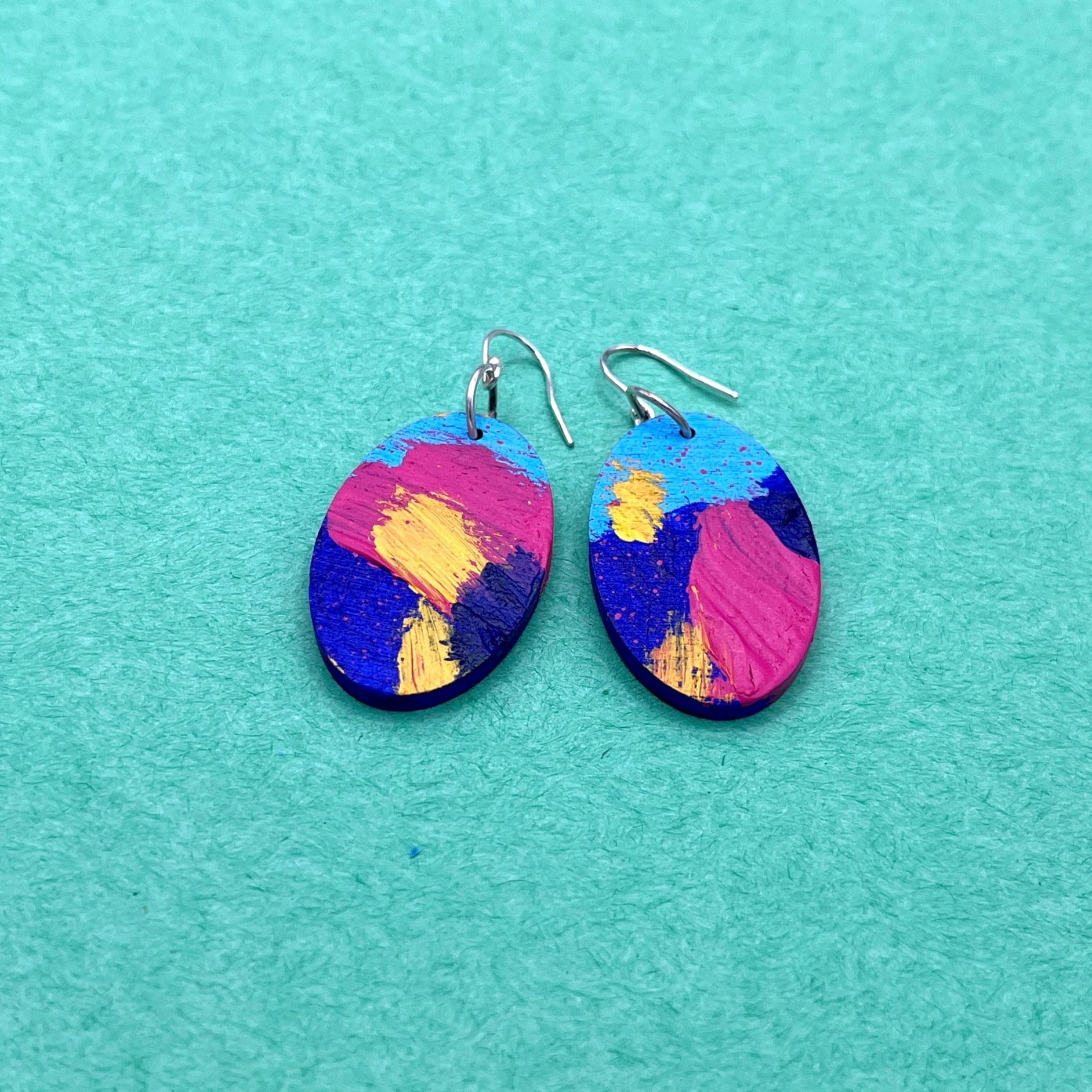 Colorful oval earrings on a teal background