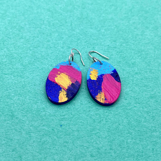 Colorful oval earrings on a teal background