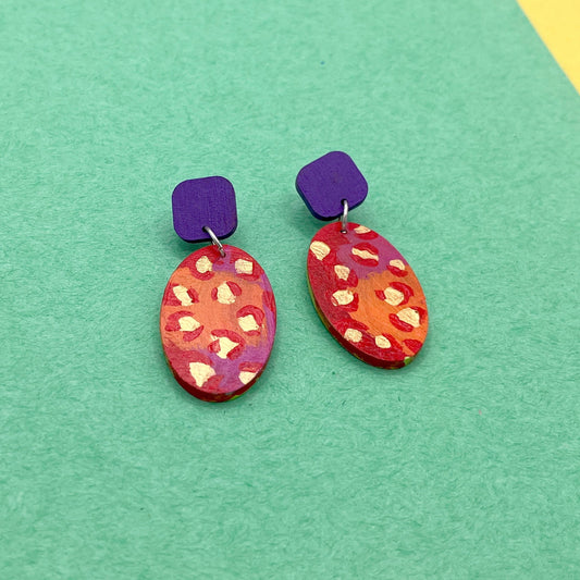 Pair of colorful oval earrings on a green background