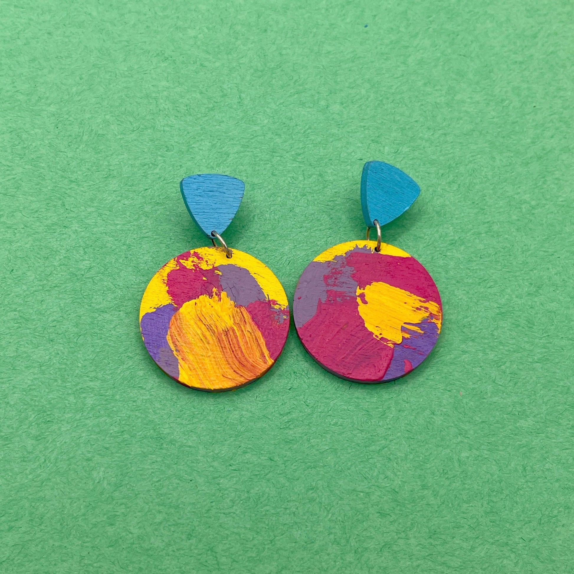 Colorful round earrings with blue accents on a green background