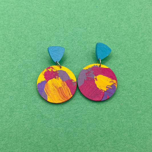 Colorful round earrings with blue accents on a green background