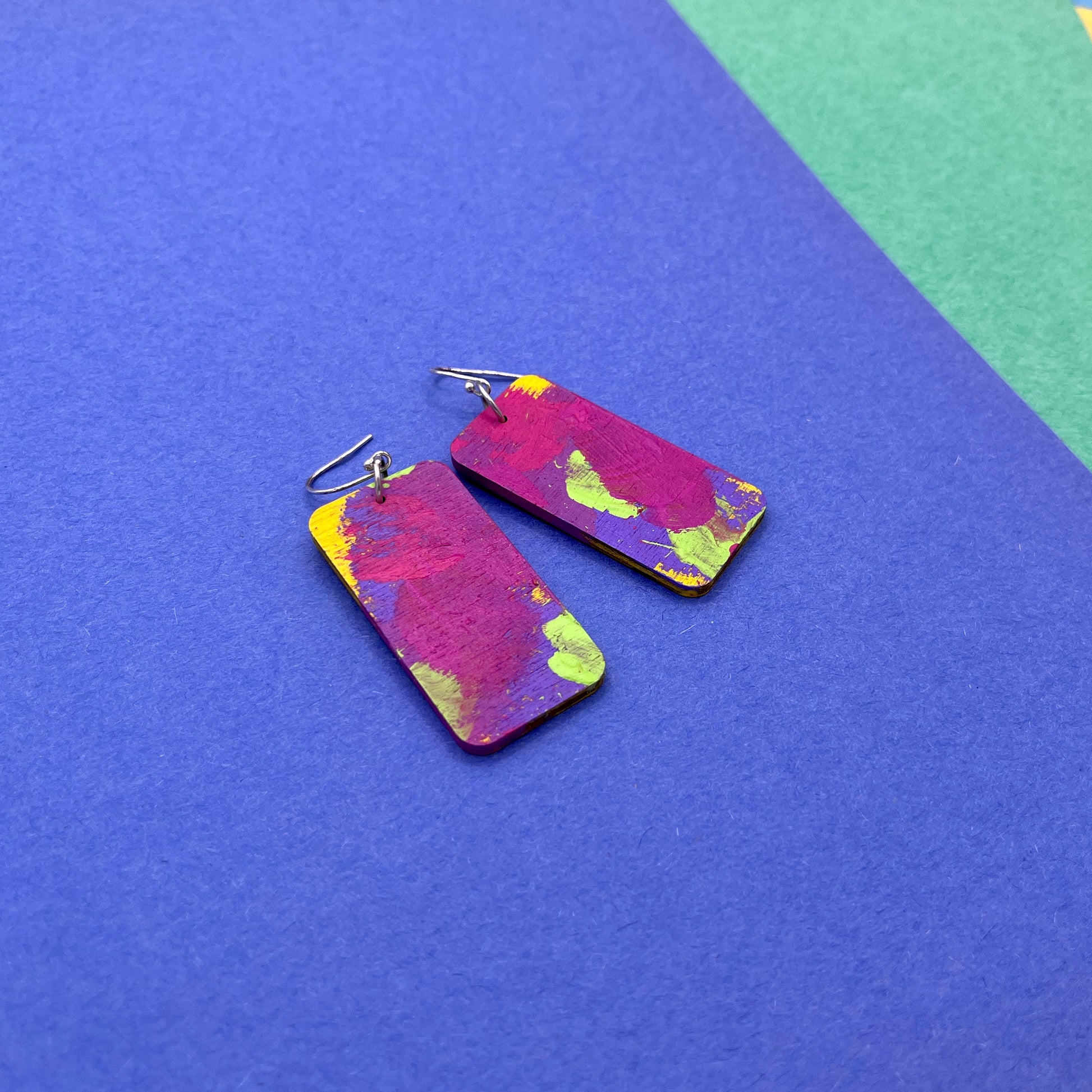 Colorful rectangular earrings on a blue and green background