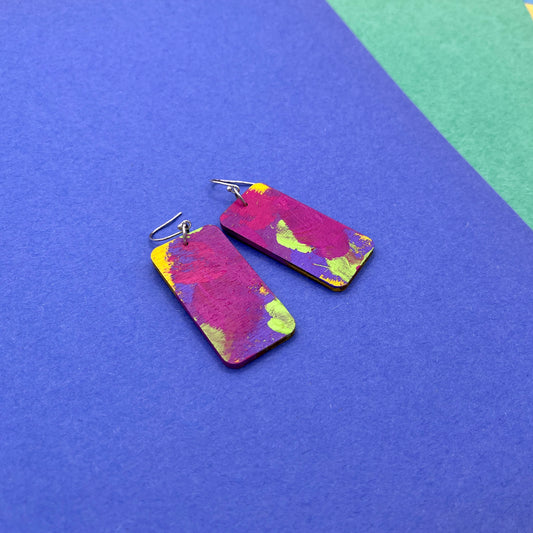 Colorful rectangular earrings on a blue and green background