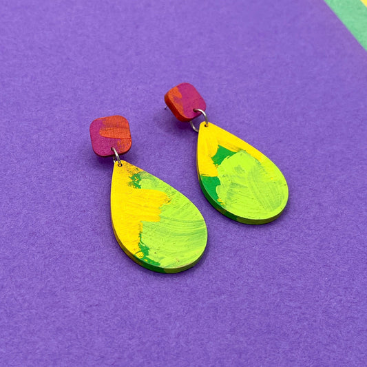 Colorful teardrop-shaped earrings on a purple background