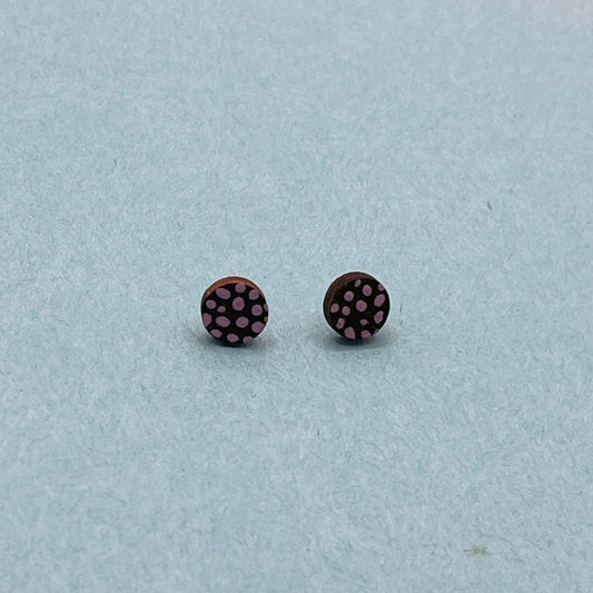 Black stud earrings on a light blue background with colorful geometric shapes.
